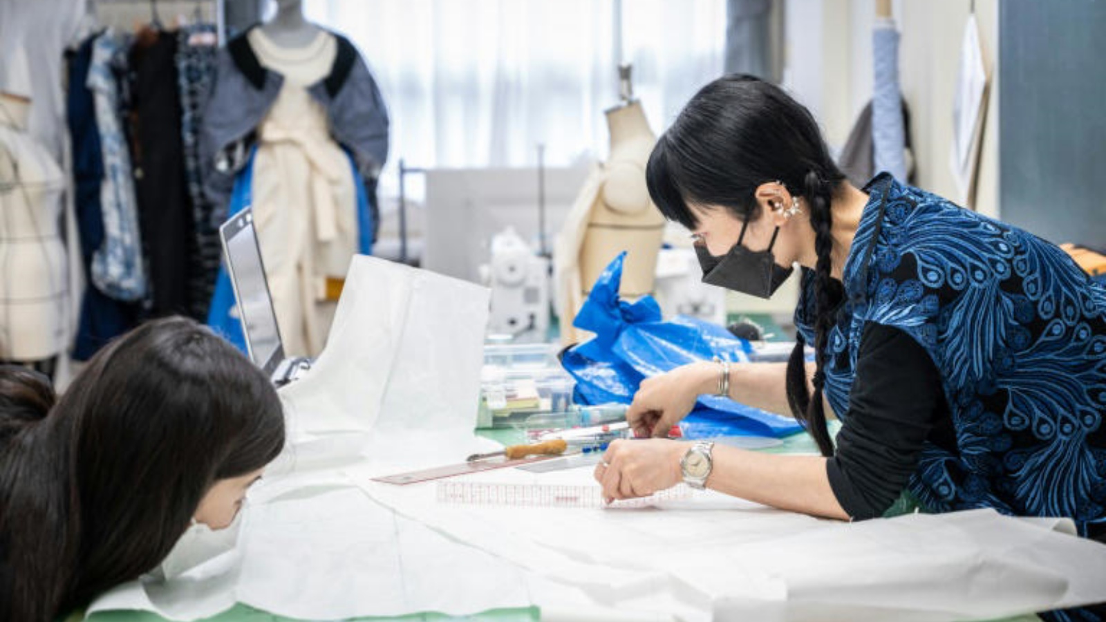 استاذة في معهد بونكا للأزياء في طوكيو تُظهر طالباً وهو يقص قماشاً في 16 سبتمبر 2022