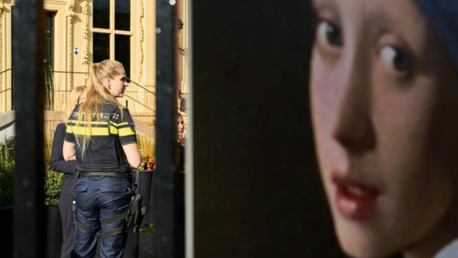 صورة التقطت في 27 أكتوبر 2022 لشرطية تقف أمام متحف موريتشيس في لاهاي (هولندا) فيما بدت إلى اليمين لوحة الفتاة ذات القرط اللؤلؤي