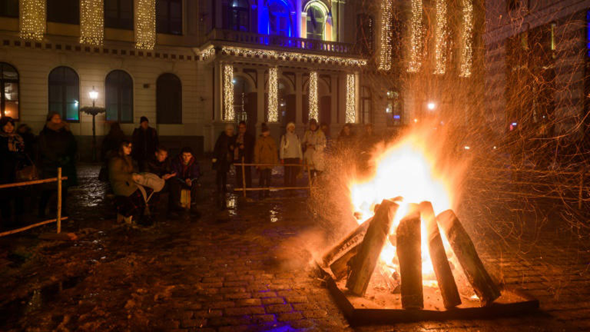 أشخاص يتجمّعون حول النيران خلال الاحتفال بالانقلاب الشتوي في ريغا في لاتفيا بتاريخ 21 كانون الأول/ديسمبر 2022 © غينتس إيفوسكانز