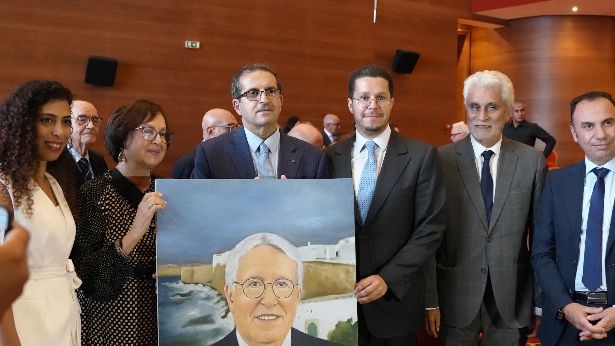 امين عام منتدى اصيلة حاتم البطيوي يتسلم لوحةً أنجزتها الفنانة الاصيلية سارة أحلالوم وأهدتها للمؤسسة في حضور السيدة ليلى الحجوي ارملة الراحل محمد بن عيسى ونجل الراحل امين بن عيسى ، ويبدو إلى جانبه محمد الحسن ولد لبات وزير خارجية موريتانيا السابق الدكتور طارق غيلان عمدة أصيلة