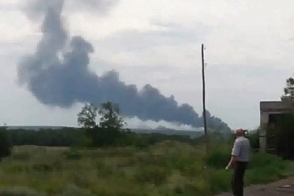 رجل أوكراني يشاهد دخانا ناتجا من احتراق الطائرة بعد سقوطها