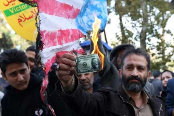 متظاهر إيراني يحرق دولارًا أميركيًا خلال تظاهرة أمام مبنى كان سابقًا مقر السفارة الأميركية في طهران بتاريخ 4 نوفمبر عشية دخول الدفعة الثانية من العقوبات الأميركية حيز التنفيذ