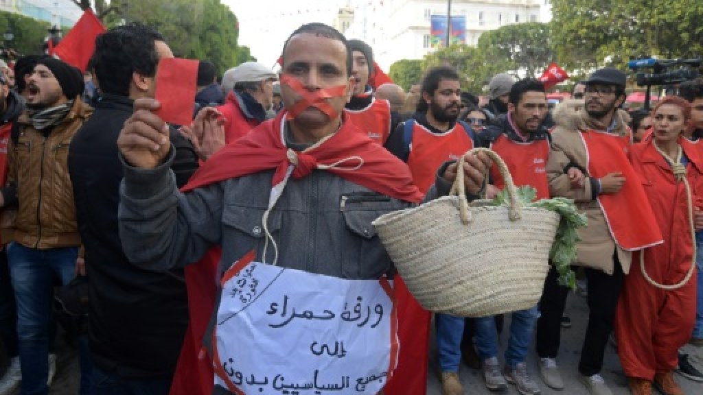 رجل يحمل لافتة تندد بغلاء المعيشة خلال الاحتفالات بالذكرى الثامنة للثورة في تونس في 14 يناير 2019