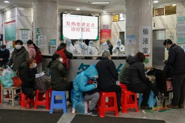 مرضى ينتظرون عاملين في المجال الطبي يرتدون بزات واقية للاحتماء من فيروس كورونا المستجد في مستشفى الصليب الأحمر في ووهان في وسط الصين في 24 يناير 2020