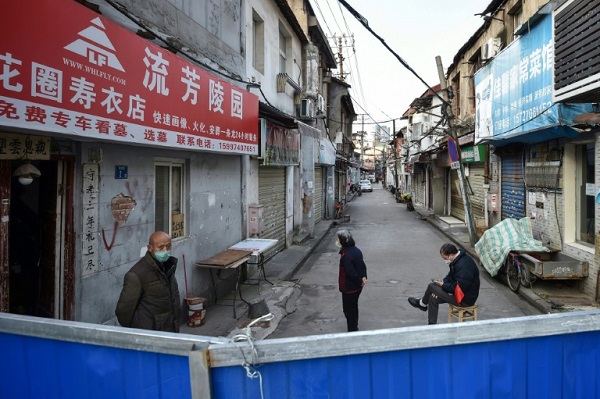 سكان خلف حاجز أمام الحي الذي يسكنوننه به في ووهان الصينية في 23 فبراير 2020