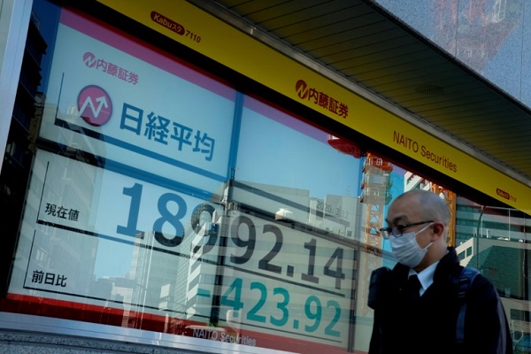 رجل يسير قبل لوحة عرض أسعار البورصة في طوكيو في 12 مارس 2020