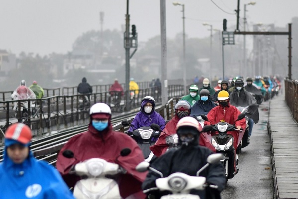أشخاص على دراجات نارية يرتدون أقنعة واقية بحماية أنفسهم من كوفيد-19 في هانوي بتاريخ 17 مارس 2020