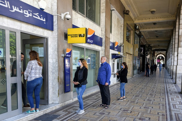 تونسيون يتلزمون مسافة التباعد المطلوبة أمام مصرف في العاصمة