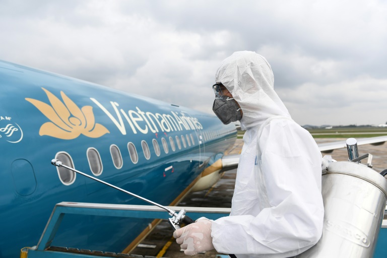عامل يعقم طائرة تابعة للخطوط الجوية الفيتنامية كإجراء وقائي من فيروس كورونا المستجد في في مطار هانوي الدولي في 3 آذار/مارس 2020