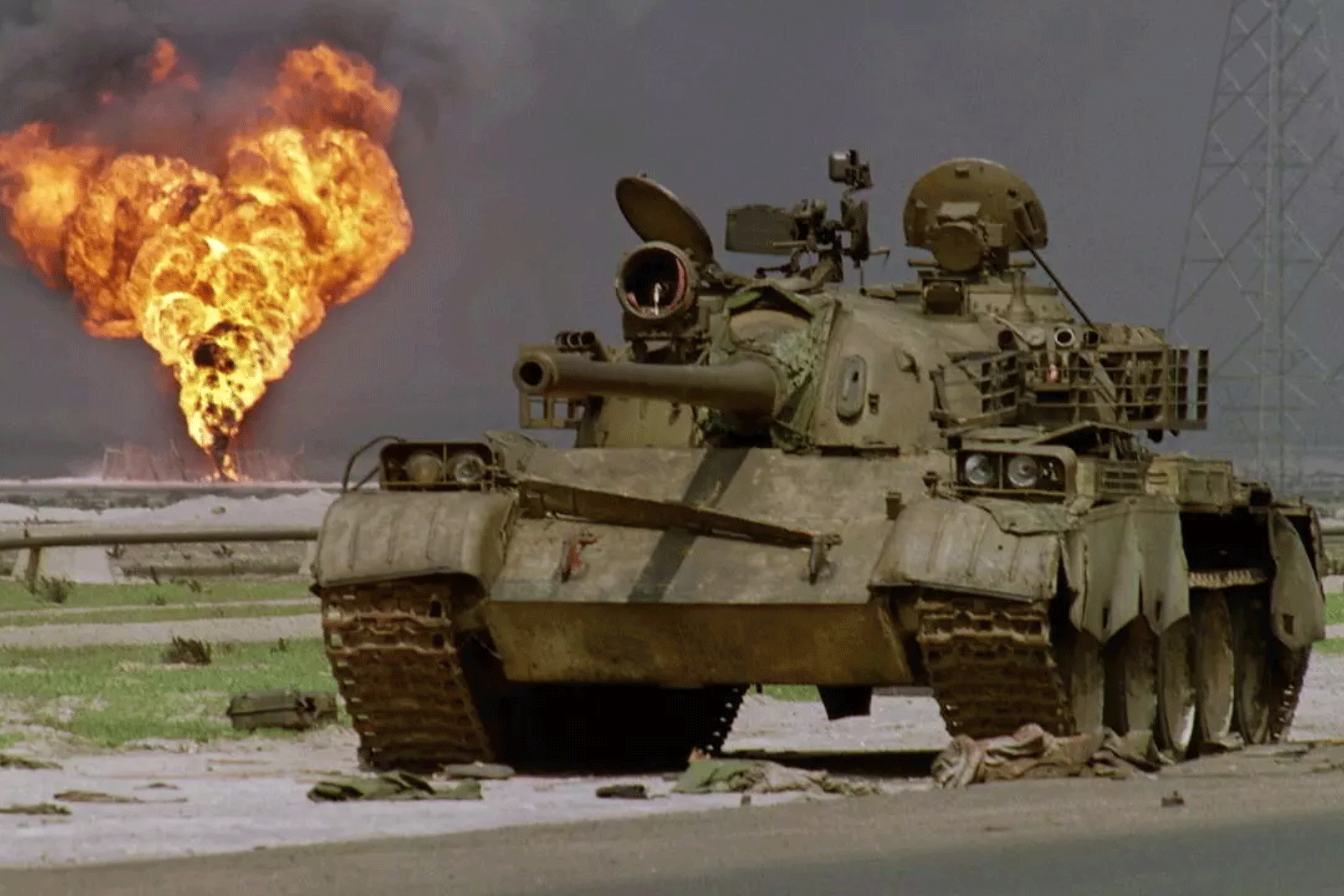 صورة من الأرشيف لدبابة عراقية متروكة في الصحراء الكويتية ويبدو حقل نفط يحترق خلفها في 2 أبريل 1991