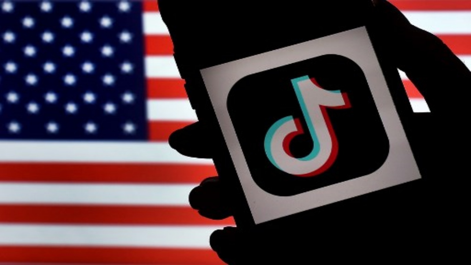  شعار تطبيق الوسائط الاجتماعية ، يتم عرض TikTok على شاشة iPhone على خلفية العلم الأمريكي في 3 أغسطس 2020 في أرلينغتون ، فيرجينيا