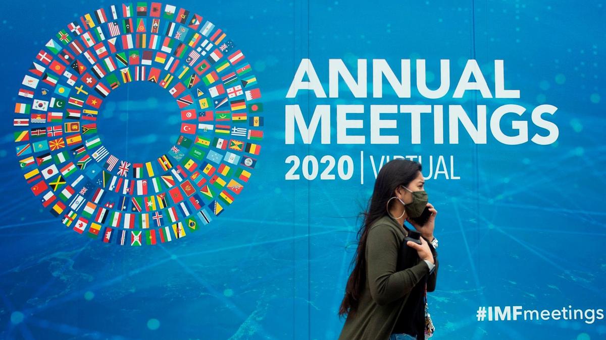 امرأة تمر بالقرب من لائحة إعلانية للمؤتمر الافتراضي لصندوق النقد الدولي في أمام مقره في واشنطن، بتاريخ 13 تشرين الأول/أكتوبر 2020