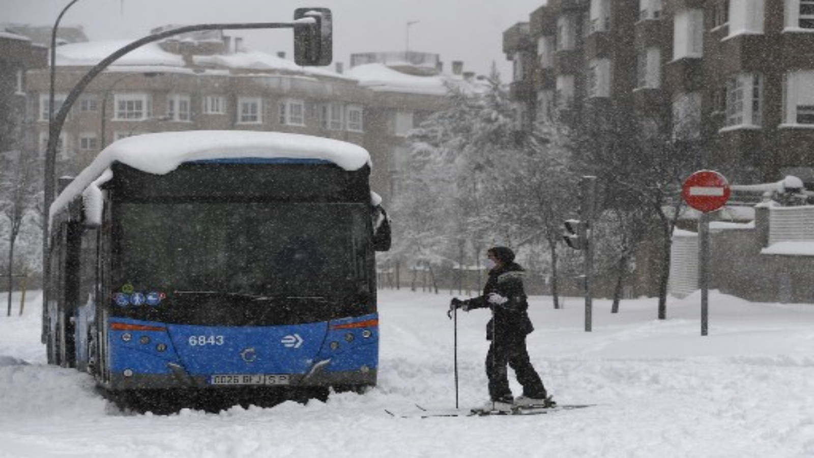 امرأة تتزلج بجوار حافلة عالقة في أحد الشوارع وسط تساقط ثلوج كثيف في مدريد في 9 يناير 2021. خلفت العواصف الثلجية في معظم أنحاء إسبانيا ثلاثة قتلى وتسببت في حدوث فوضى في معظم أنحاء البلاد ، مما أدى إلى محاصرة سائقي السيارات وإغلاق خطوط السكك الحديدية والجوية بالعاصمة