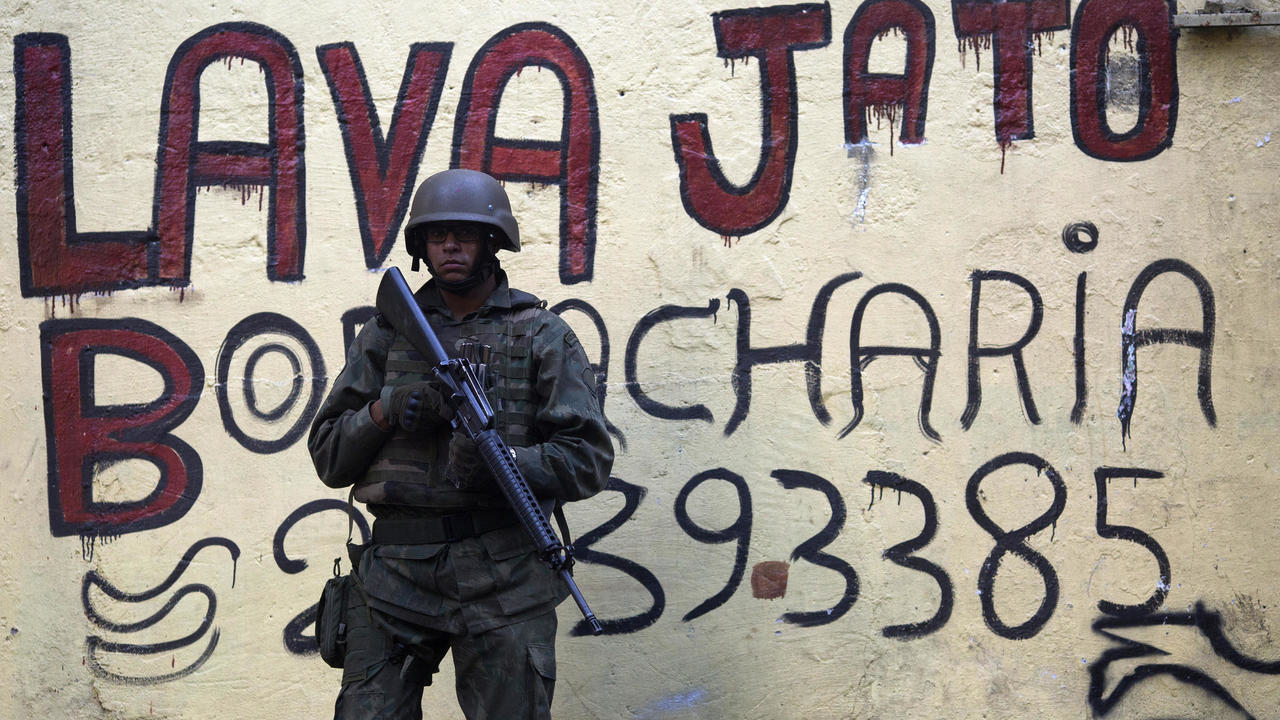 جندي برازيلي أمام رسم غرافيتي يروّج لقضية 