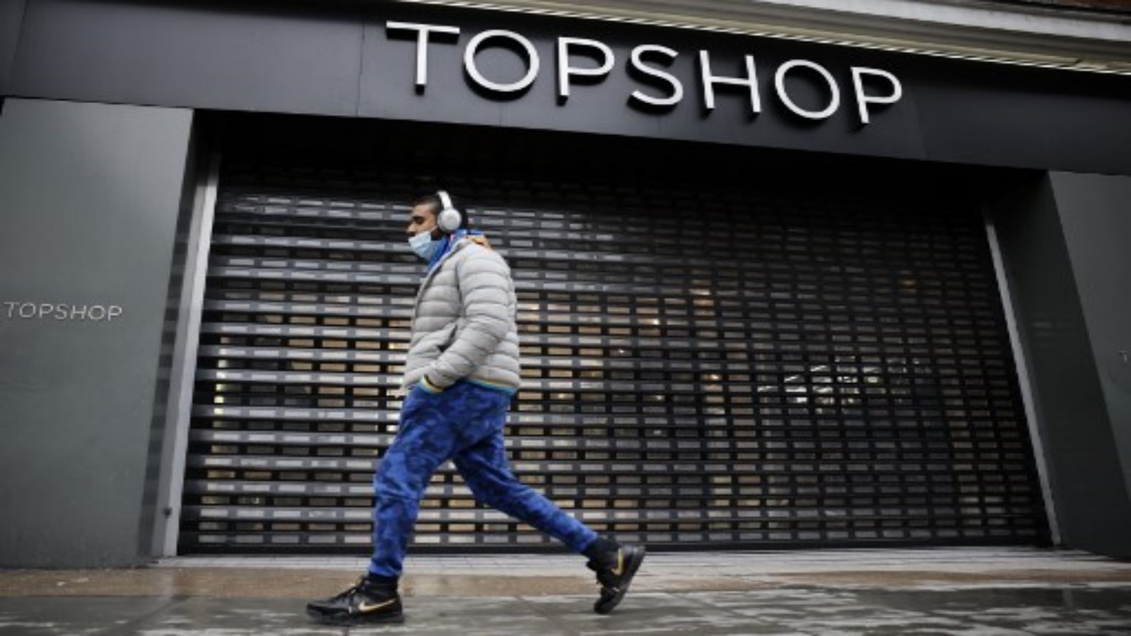 أحد المشاة يمشي أمام المدخل المغلق لمتجر توب شوب للأزياء مغلق من خلال نافذة في لندن في 1 فبراير 2021