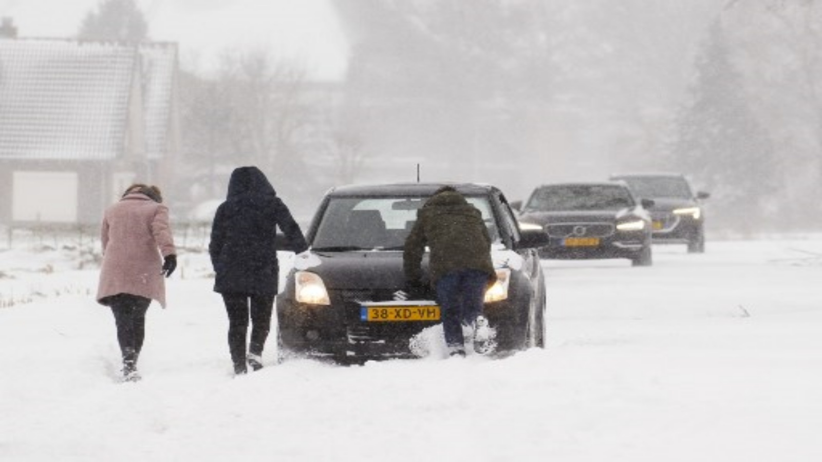 شخاص يدفعون سيارة عالقة بعد تساقط الثلوج في هارلم ، بالقرب من أمستردام ، هولندا ، في 7 فبراير 2021