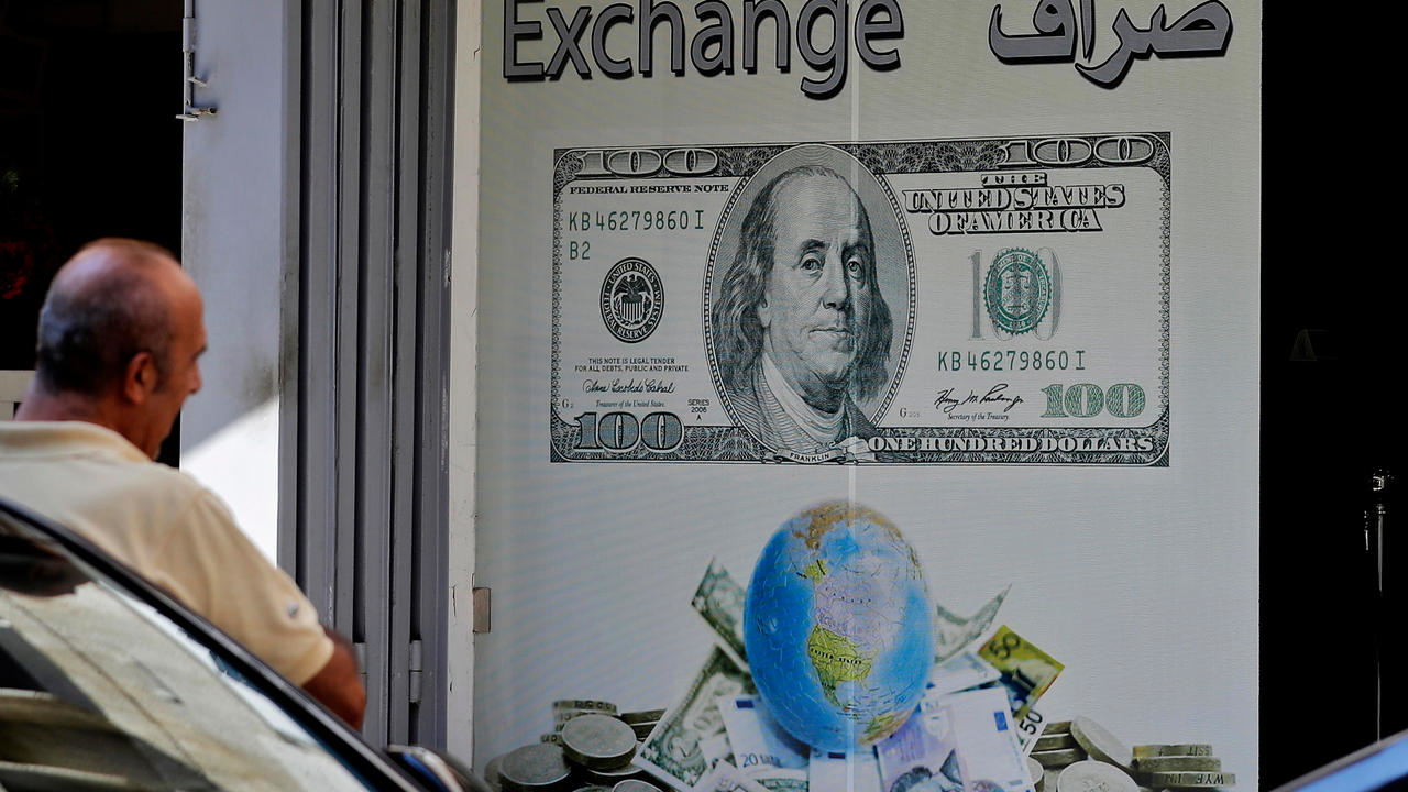 رجل جالس أمام مكتب صيرفة في بيروت في 1 تشرين الأول/أكتوبر 2019. أزمة اقتصادية متصاعدة في لبنان منذ فترة أدت مؤخرا إلى ارتفاع سعر صرف الليرة اللبنانية مقابل الدولار في السوق السوداء