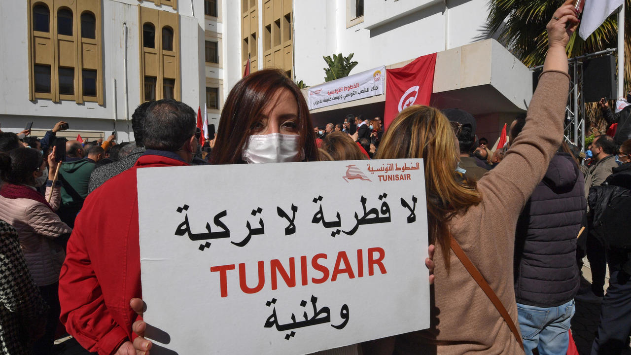 موظفة من شركة الخطوط الجوية التونسية ترفع لافتة خلال تظاهرة أمام مقر الشركة في العاصمة التونسية في 19 شباط/فبراير 2021