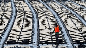 تُظهر هذه الصورة التي التقطت في 22 يناير 2021 عاملاً يسحب كابلًا على طول مزرعة طاقة شمسية عائمة قبالة الساحل الشمالي لسنغافورة عبر ولاية جوهور الماليزية