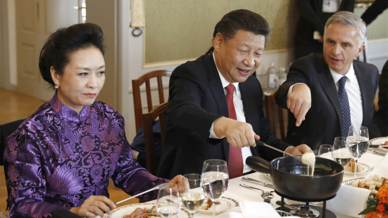 الرئيس الصيني شي جين بينغ (وسط) وزوجته بينغ ليوان، يتذوقان فوندو الجبن مع وزير الخارجية السويسري ديدييه بورخالتر بيتر كلاونزر