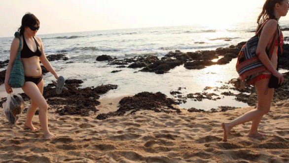 سائحتان على شاطئ في الهند، التي عطل كورونا الكثير من القطاعات الاقتصادية فيها، ومنها السياحة