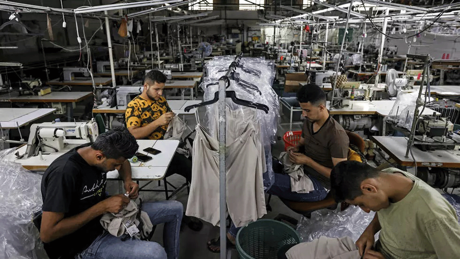 خياطون فلسطينيون يعملون في مصنع ملابس فارغ في المنطقة الصناعية في قطاع غزة في 21 حزيران/يونيو 2021