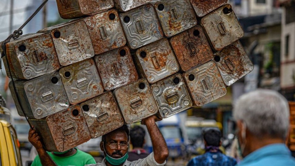 مواطن هندي في بومباي يحمل عبوات من التنك لبيعها والترزق بثمنها