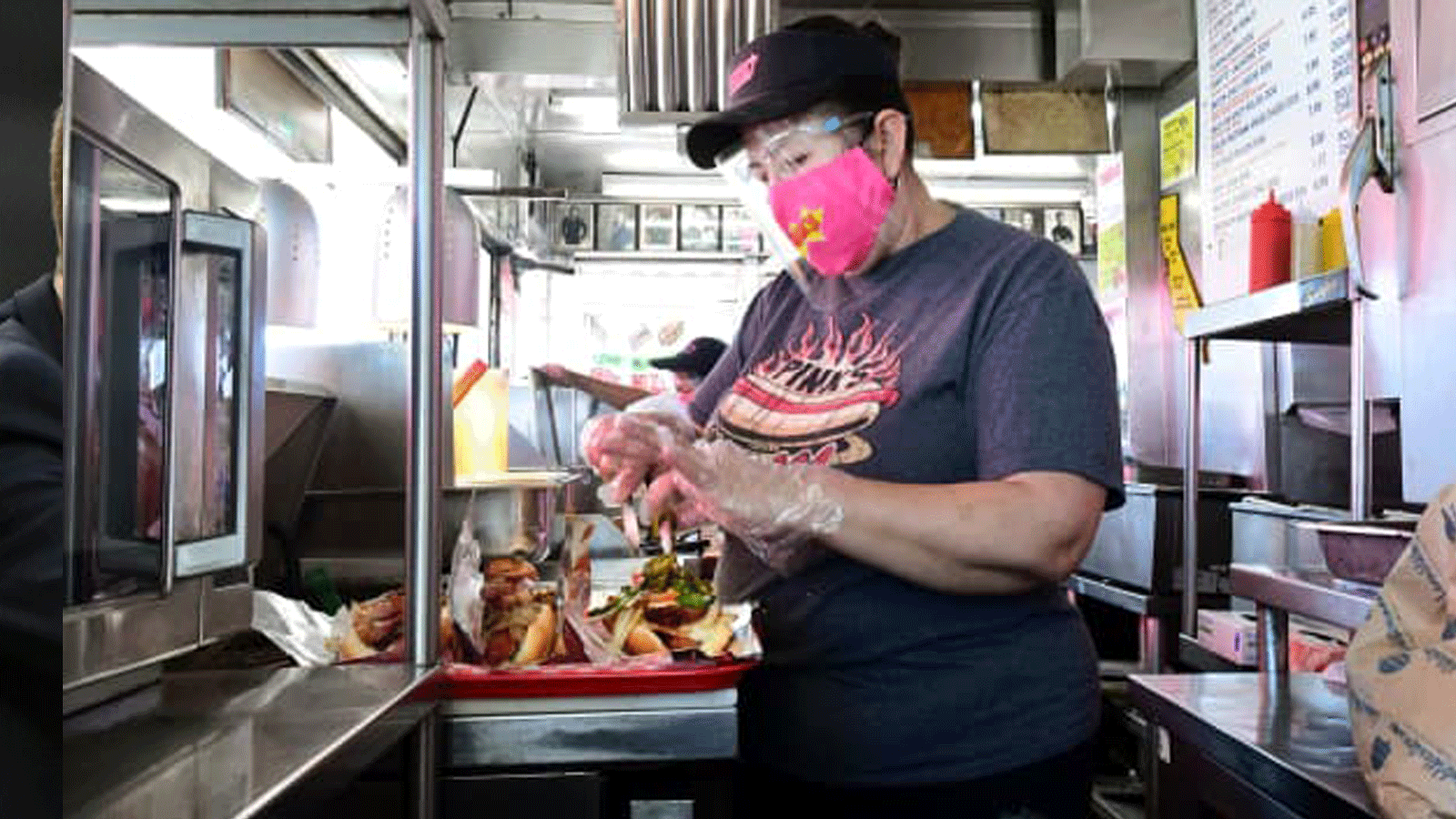 عمال المطعم يرتدون أقنعة الوجه والقفازات بعد إعادة افتتاح مطعم Pink’s Hot Dogs في لوس أنجلوس في 1 آذار/مارس 2021 في لوس أنجلوس، كاليفورنيا.