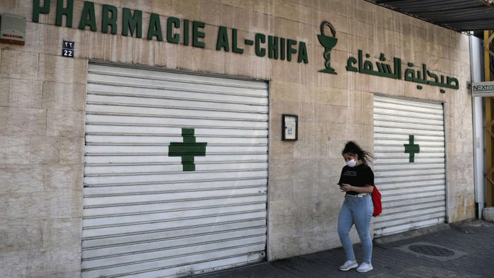 امرأة تمر أمام صيدلية مغلقة في بيروت، لبنان، 11 يونيو/ حزيران 2021