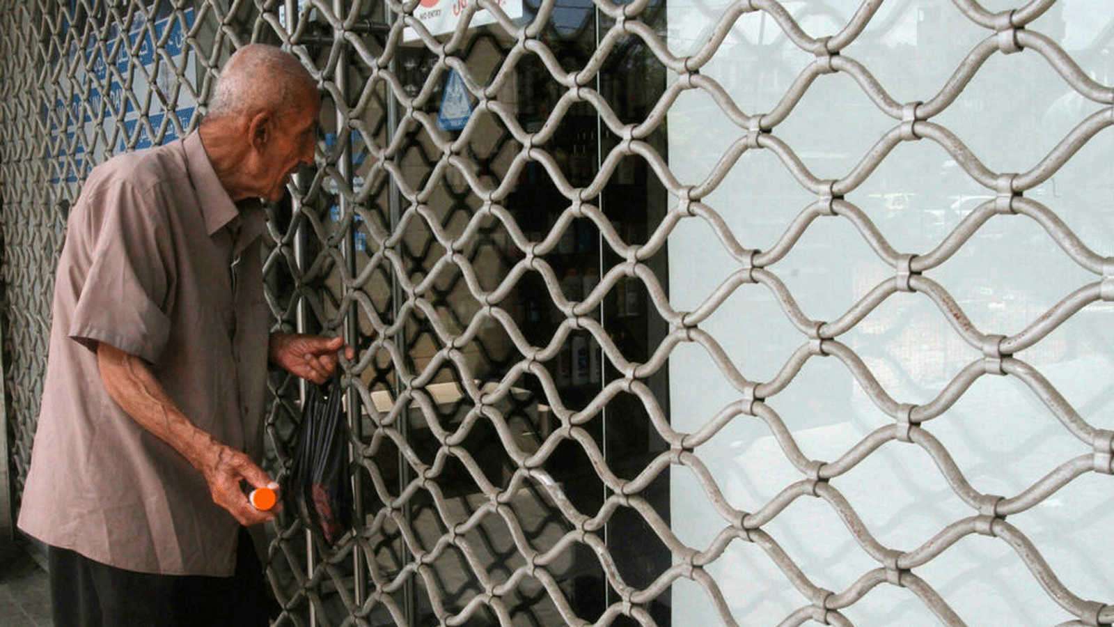 رجل مسن خارج صيدلية مغلقة في مدينة صيدا جنوب لبنان، 9 تموز/ يوليو 2021