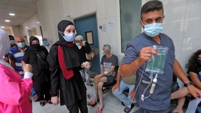 مسعف يساعد مريضة بينما ينتظر الآخرون في ممر في مستشفى رفيق الحريري الجامعي في العاصمة اللبنانية بيروت في 23 تموز/ يوليو2021