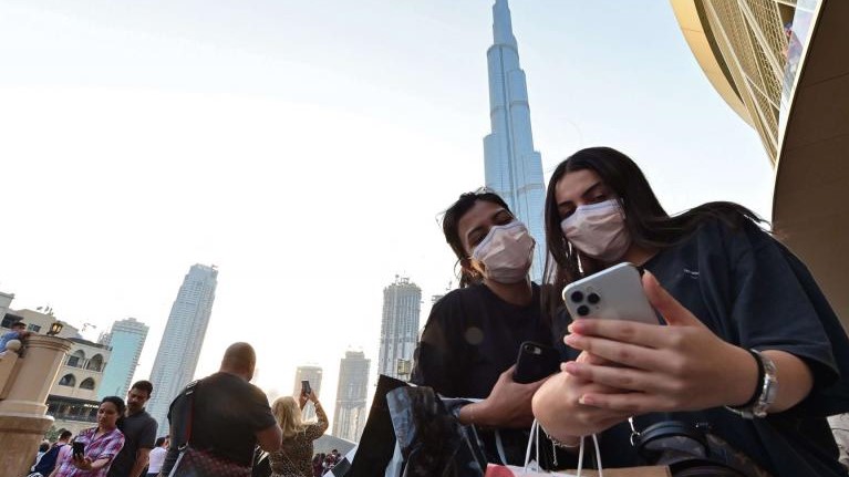 سائحتان تلتقطان صورة سيلفي أمام برج خليفة في دبي وهما ترتديان القناع الطبي الواقي من كورونا