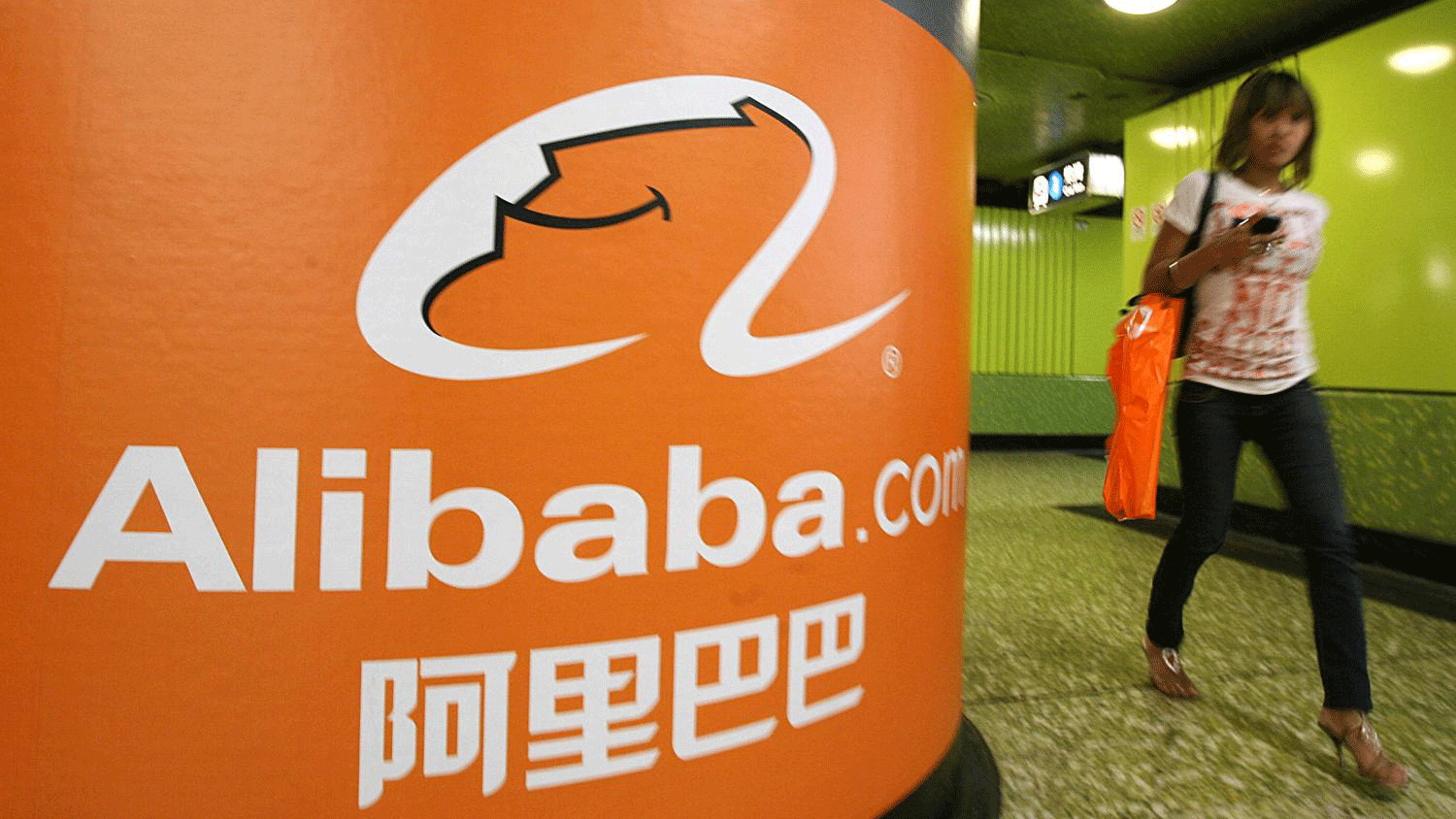 امرأة تمر بالقرب من لوحة إعلانية لشركة علي بابا في هونغ كونغ