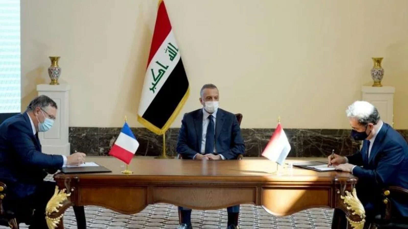 ممثل عن الحكومة العراقية (يمين) ورئيس توتال إنرجيز باتريك بوياني (يسار) يوقعان العقد بحضور رئيس الوزراء العراقي مصطفى الكاظمي في العاصمة بغداد. بتاريخ 5 أيلول/ سبتمبر 2021.