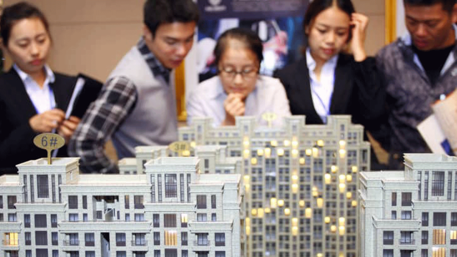 العملاء وأصحاب العقارات ينظرون إلى نماذج البناء في معرض في جياشان في شرق الصين.