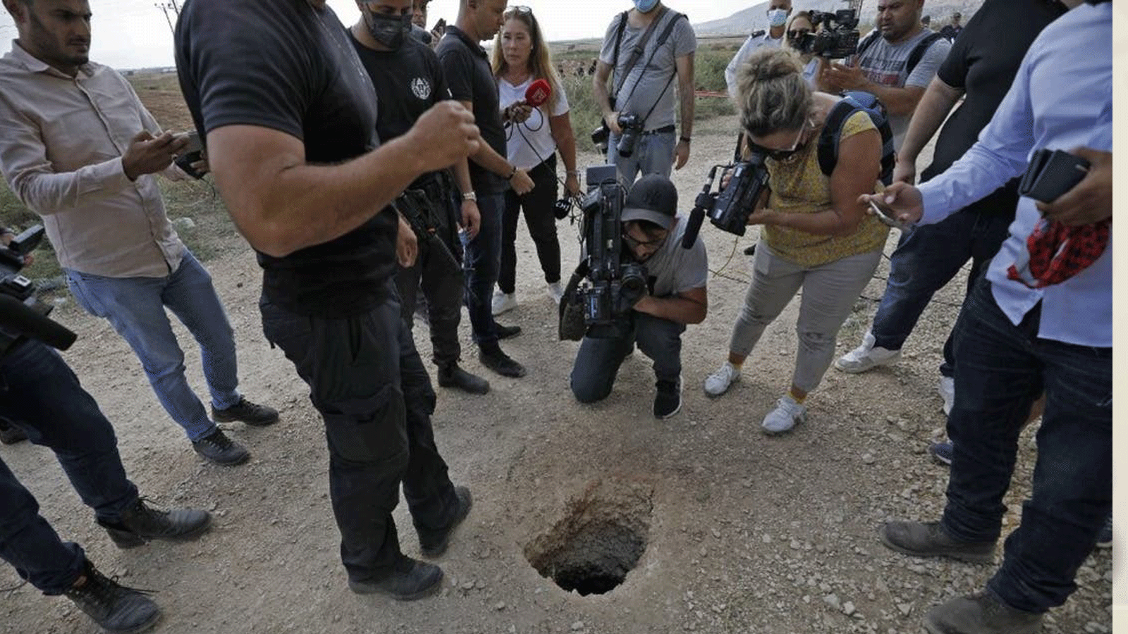 الشرطة والصحفيون يتجمعون حول حفرة استخدمها ستة فلسطينيين للفرار من سجن جلبوع بعد أن حفروا نفقًا تحت مغسلة في شمال إسرائيل. 6 أيلول/ سبتمبر 2021