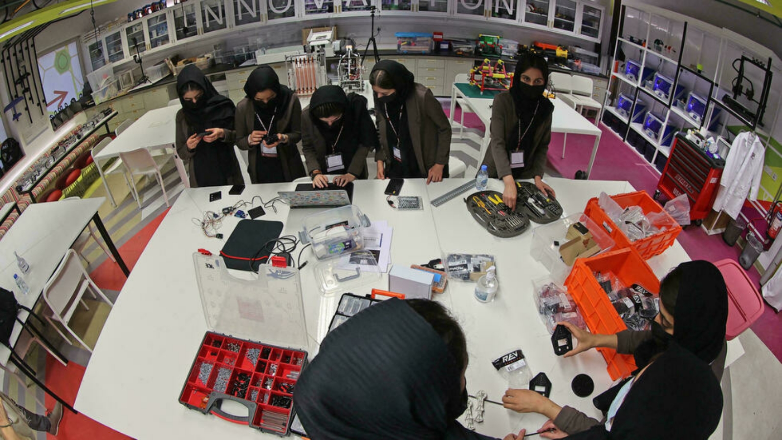 أعضاء من فريق الروبوتات الأفغاني الذي يتكون بالكامل من فتيات يجمعن مكونات لوحة دوائر كهربائية يبنونها في مختبر جامعة تكساس إيه آند إم في العاصمة الدوحة.