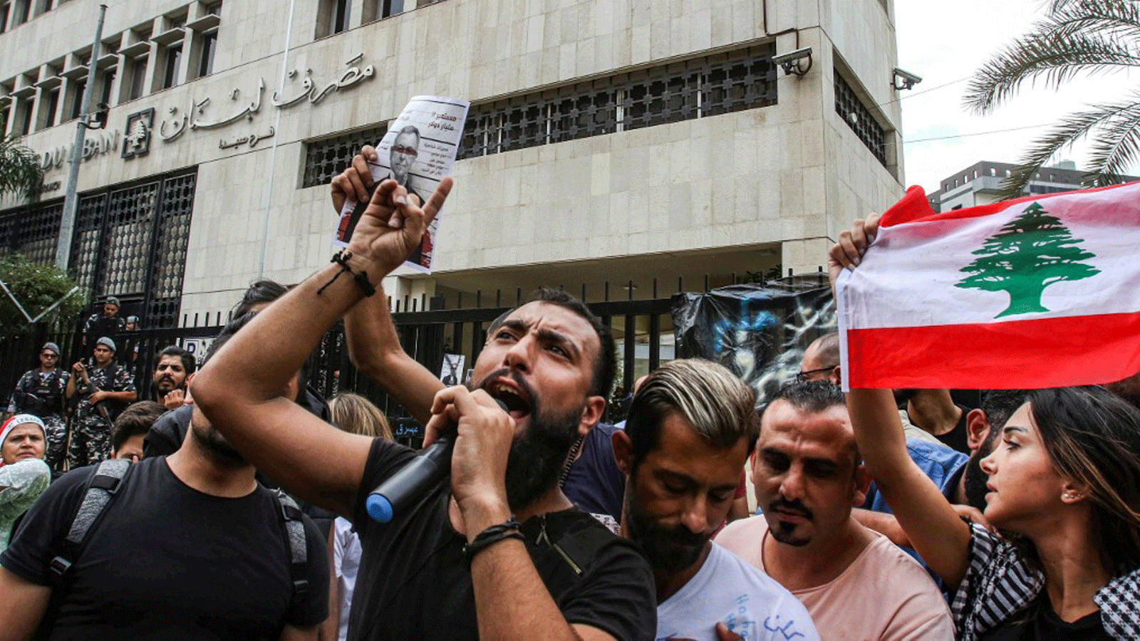 متظاهرون لبنانيون يرفعون لافتات تندد بوزير المالية السابق فؤاد السنيورة أثناء تجمعهم في اليوم الثامن للاحتجاج على زيادة الضرائب والفساد الرسمي خارج فرع البنك في مدينة صيدا الجنوبية. 24 تشرين الأول/أكتوبر 2019.