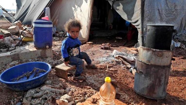 صورة من الأرشيف لطفلة سورية تجلس خارج خيمة في أحد مخيمات النازحين بإدلب 