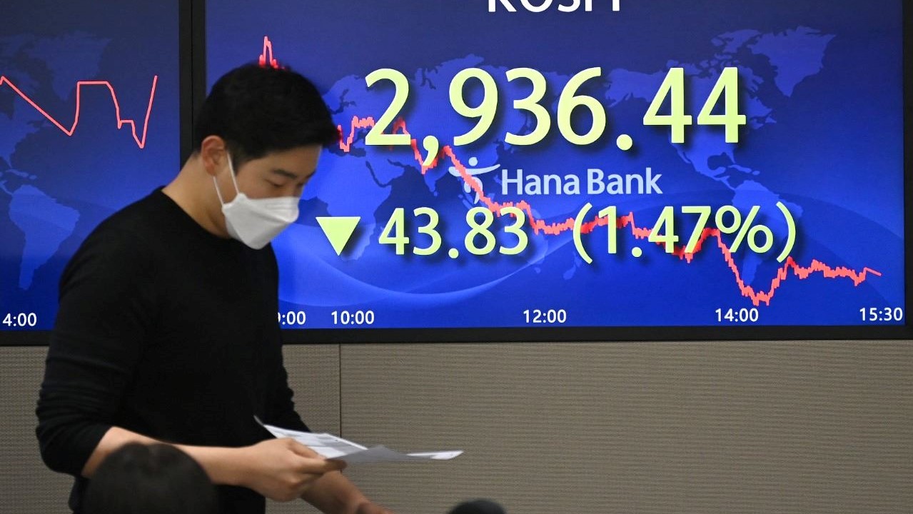 تاجر عملات يمر قرب شاشة تعرض مؤشر الأسهم القياسي لكوريا الجنوبية في غرفة التداول في 