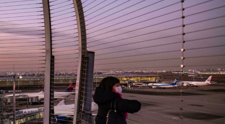 امرأة تنظر إلى الطائرات في مطار هانيدا الدولي بطوكيو في 29 نوفمبر 2021 ، حيث أعلنت اليابان عن خطط لحظر جميع المسافرين الأجانب الجدد بسبب متحور أوميكرون