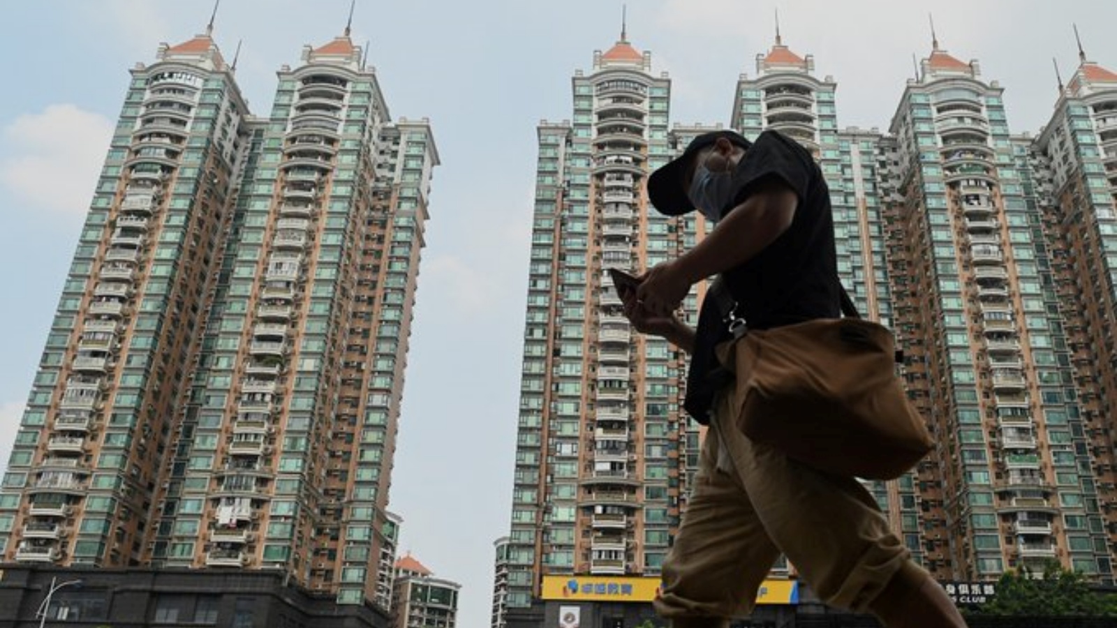 رجل يمشي بجانب أحد المشاريع السكنية الضخمة لشركة إيفرغراند في الصين.