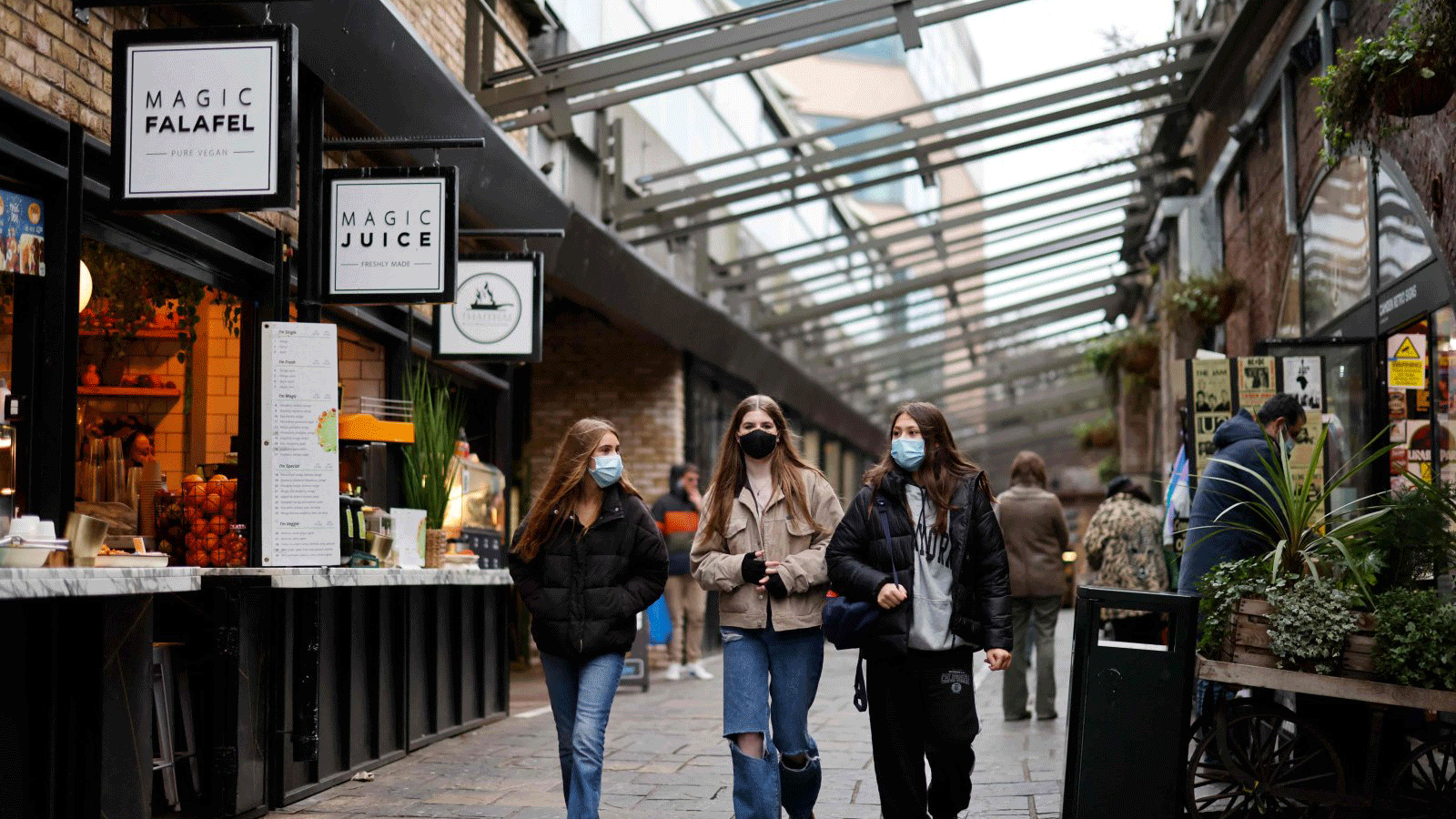 متسوقون يرتدون أغطية للوجه لمكافحة انتشار فيروس كورونا، يمشون أمام المتاجر في سوق كامدن في لندن، المملكة المتحدة، 7 كانون الثاني/يناير 2022. 