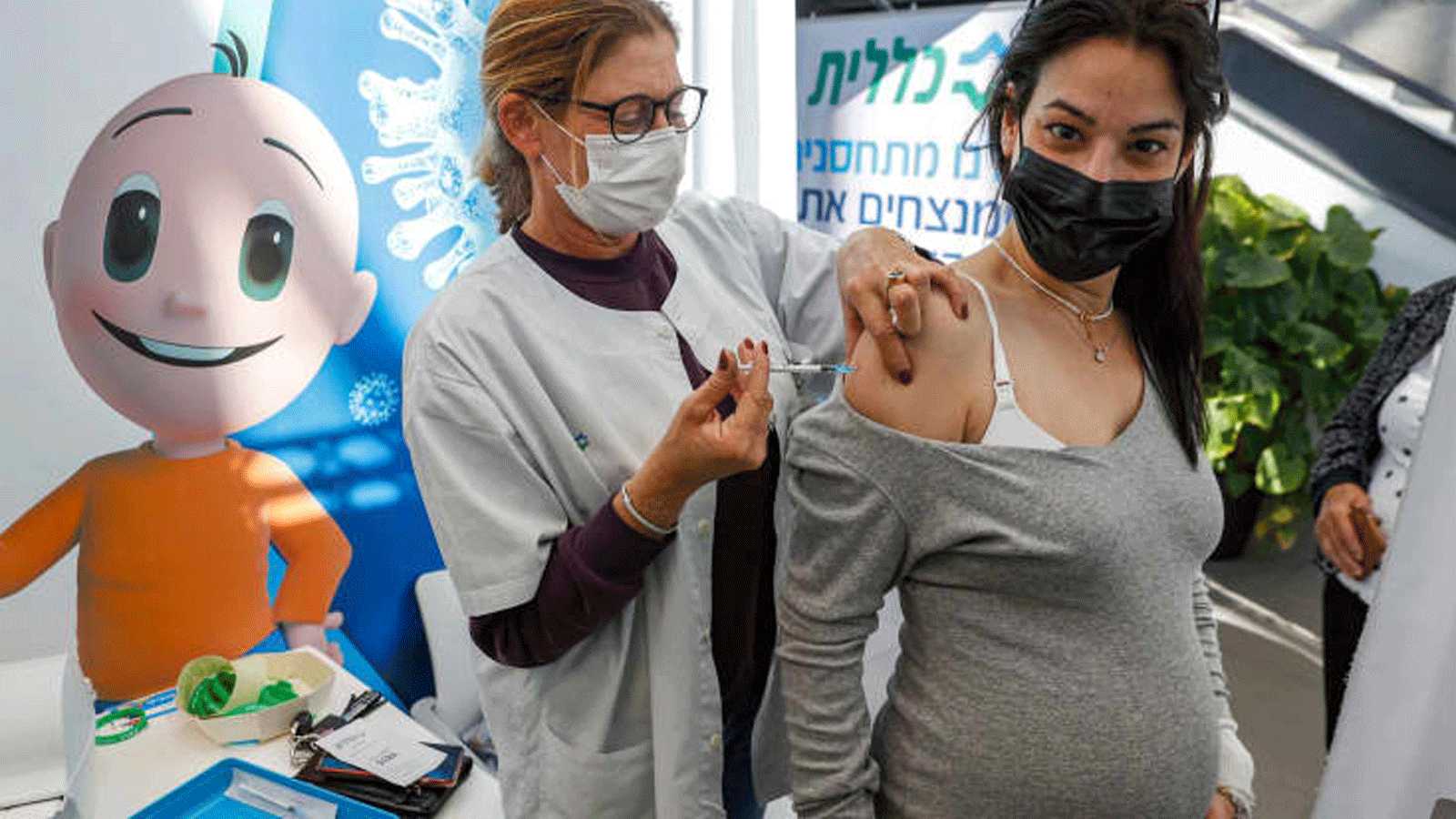  عاملٌ صحي يعطي جرعة من لقاح فايزر-بيونتيك COVID-19 المضاد لكورونا لامرأة حامل في خدمات الصحة كلاليت، في مدينة تل أبيب/ إسرائيل. 23 كانون الثاني/ يناير 2021