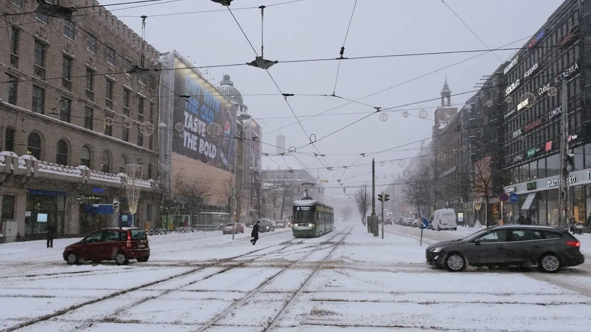 تُظهر صورة تم التقاطها في 12 يناير 2021 سيارات وقطار ترام يسير في شارع مانرهايمينتي في هلسنكي، بعد تساقط الثلوج