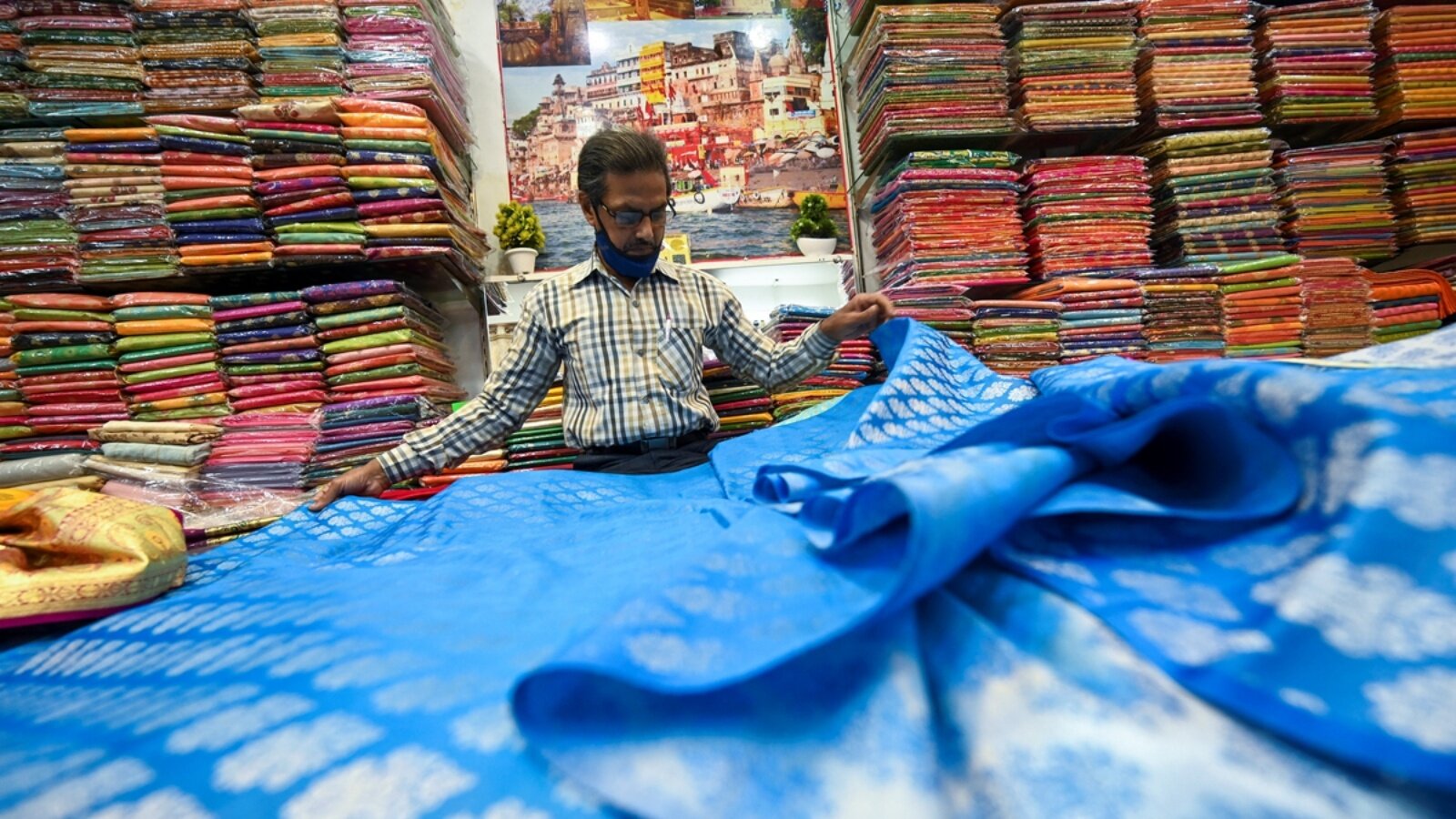 صاحب متجر يعرض ساري باناراسي التقليدي في متجر في فاراناس، الهند، في 20 نوفمبر 2021