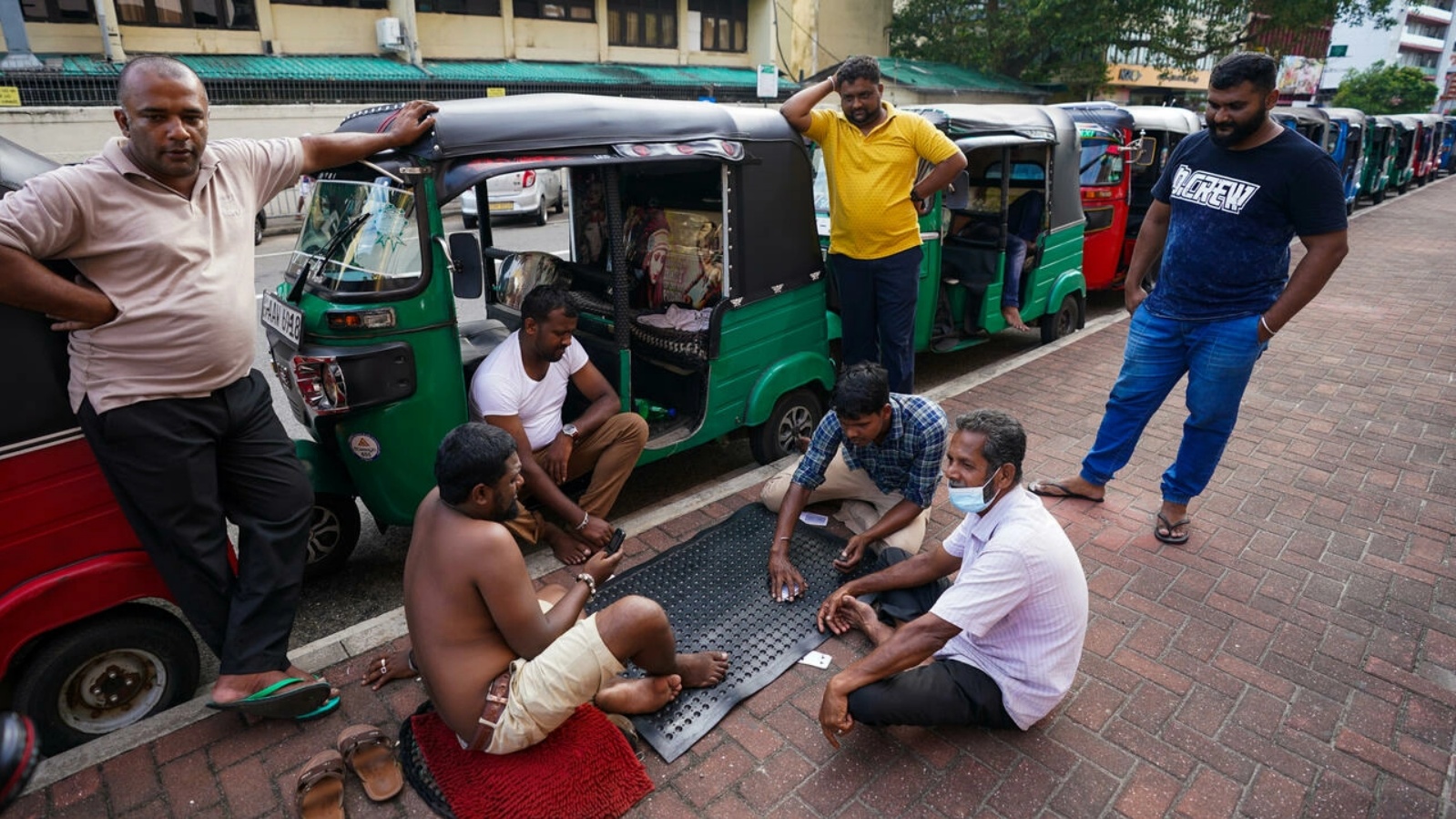 صورة مؤرخة في 18 يونيو 2022 لمواطنين سريلانكيين يلعبون بالورق خلال انتظارهم في الدور لتعبئة وقود في كولومبو 