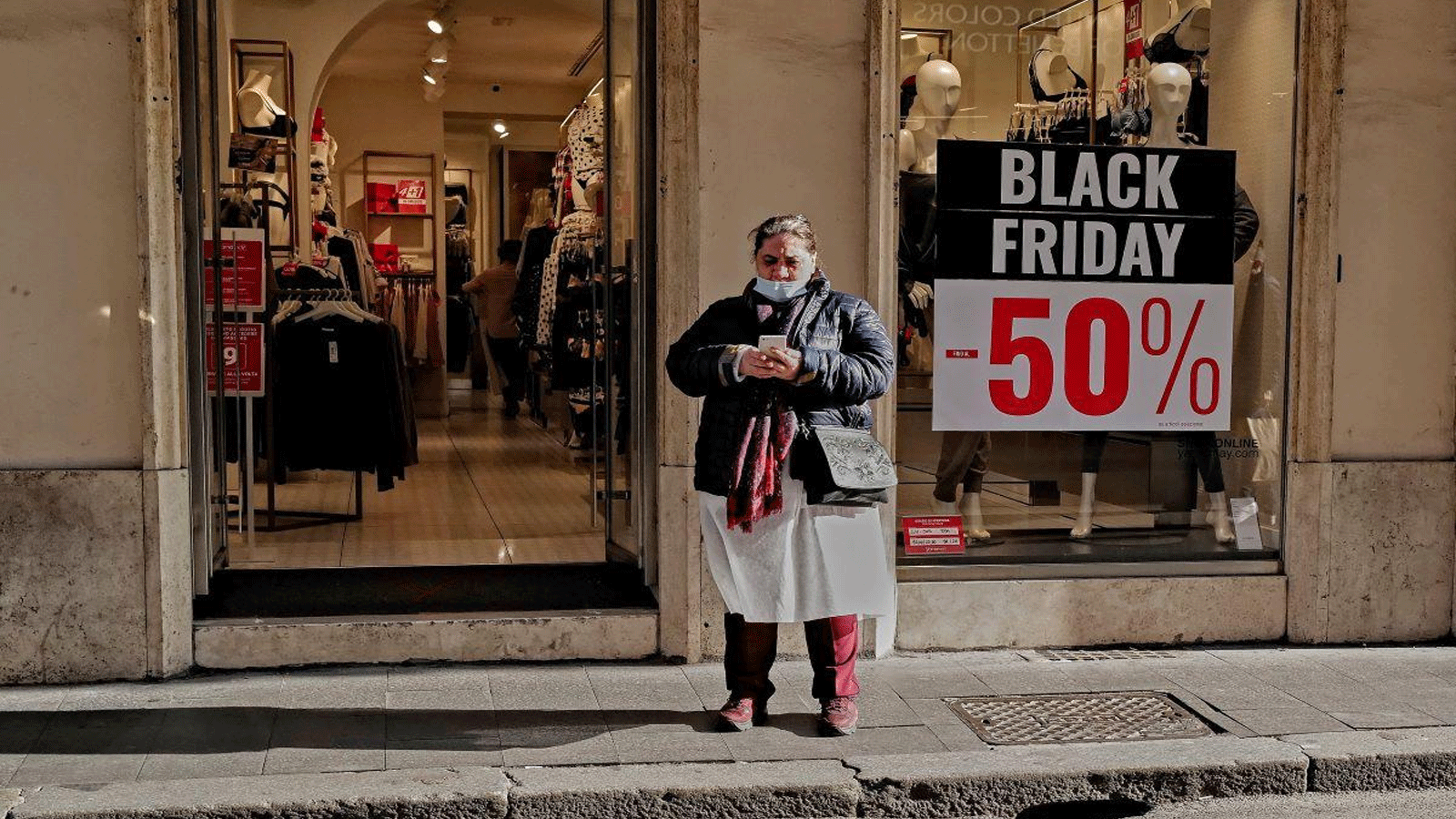 امرأة تقف أمام محل ألبسة في روما