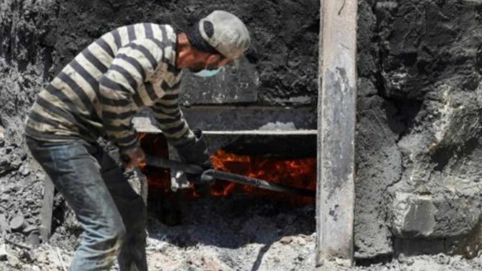 عامل فلسطيني يشعل النار في حوض يضم طنا من البلاستيك لإنتاج وقود في قطاع غزة في 23 أغسطس 2022