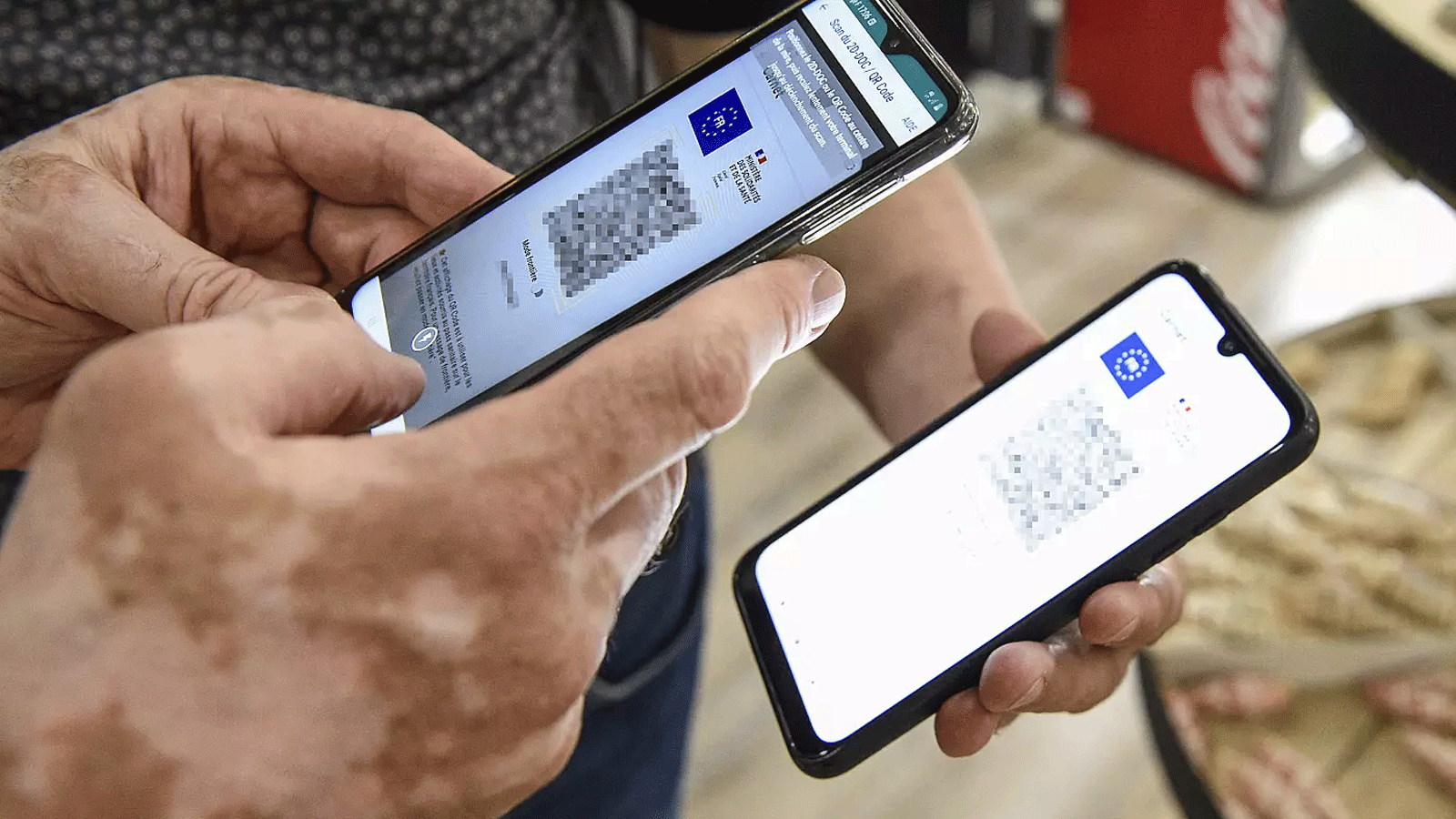 شخص يستخدم تطبيق التحقق من المرور على هاتف ذكي للتحقق من تصريح المرور الصحي المعروض على هاتف ذكي في أمنفيل، شرق فرنسا، في 22 تموز\يوليو 2021